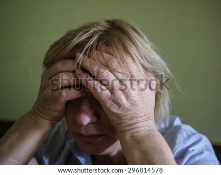 middle-aged woman in despair props her head with hands