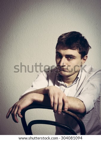 young man in a light shirt with open collar. resentful