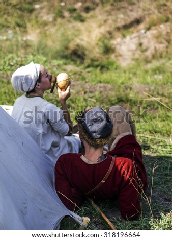 KIEV, UKRAINE - Sept 19, 2015: Enactors in medieval clothes resting near the tent -- In the historical festival \