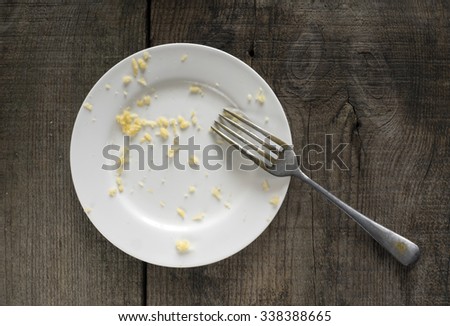 empty white plate with crumbs of grated cheese on old weathering wooden table