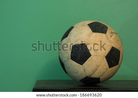 An old soccer ball on wooden table with retro green paint wall