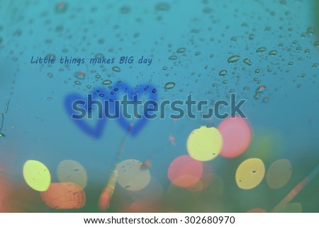 Inspirational Typographic Quote - Little things makes big day. Rain drops and two hearts write on window with light bokeh, rainy season abstract background.