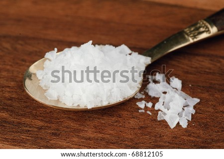 Spoon full of sea salt on wood