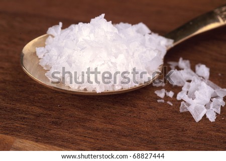 A spoon full of sea salt  on a wooden table
