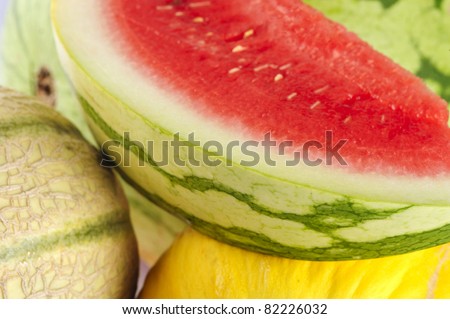 A slice of water melon, a water melon, a honey dew melon and a musk melon.