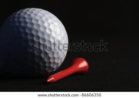 Golf ball with red tee on black background