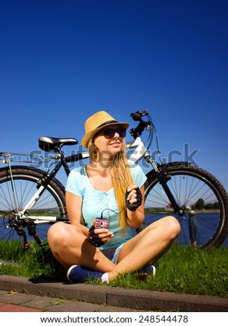 young beautiful girl with bike,listening to music,  outdoor