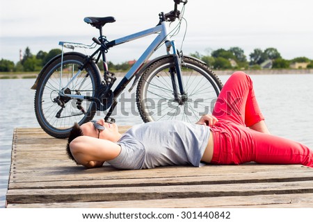 young man lying at the beach and resting after bicycle ride