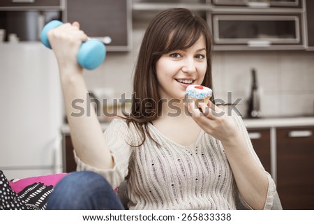 Young woman eating cupcake and exercising