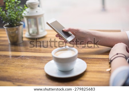 Surfing the net on smart phone while having coffee
