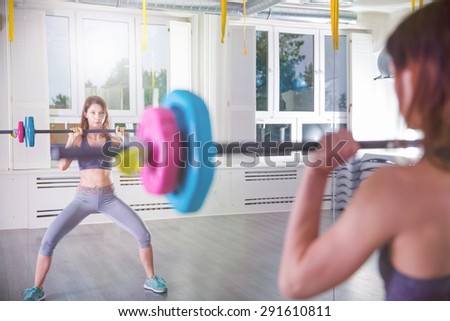 Mirror reflection of a fitness instructor with barbell