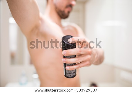 Man using antiperspirant in bathroom