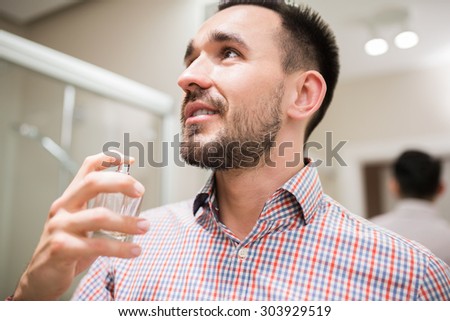 Portrait of a latin handsome man using perfume in bathroom