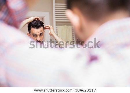 Man doing his hairstyle in bathroom