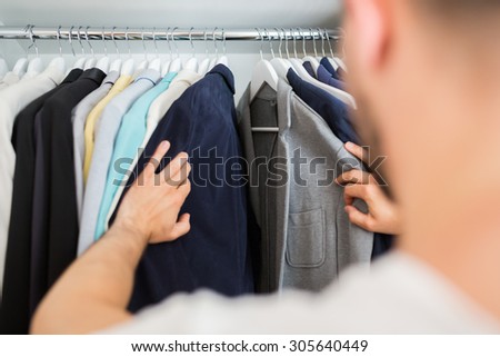 Unrecognizable man choosing jacket in his wardrobe