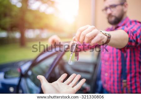 Man standing by the car and giving back car keys