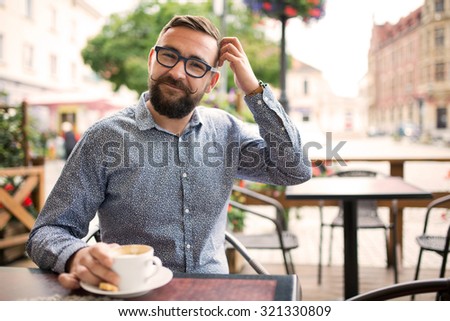 Ashamed smiling man sitting in a cafe and scratching his head
