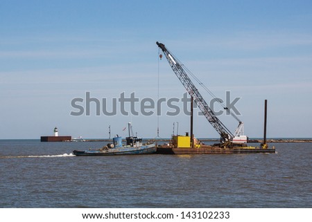 Barge And Crane:  A small tugboat pushes a construction crane sitting on a barge across the harbor at Cleveland, Ohio