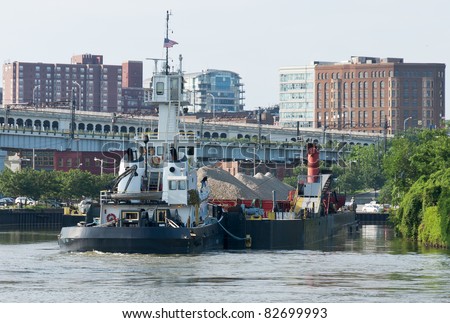 Cuyahoga River Tug    A tug boat slowly maneuvers a barge filled with rock and sand around one of the many bends in the Cuyahoga River in Cleveland, Ohio