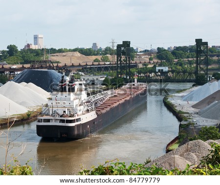 Train and Ship Two modes of industrial transportation including a Great Lakes bulk carrier ship waiting for a drawbridge to be raised and a line of railroad coal cars crossing an elevated viaduct