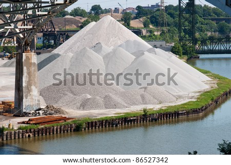 Aggregate Material:  Various aggregate materials used in the concrete making process are piled together on the bank of the Cuyahoga River in the flats industrial district of Cleveland, Ohio