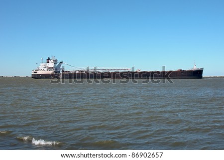 A Great Lakes self-unloading bulk carrier ship navigates the waters inside the Lake Erie break wall heading to the Cleveland Bulk Terminal dock
