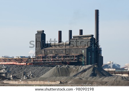 Rust Belt Steel Mill:   A large steel manufacturing plant surrounded by piles of coal and coke located in the American rust belt city of Cleveland, Ohio