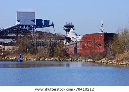 An articulated tugboat and barge is being loaded with taconite for delivery to a steel mill.  This bulk terminal is located in the Cleveland Harbor on Lake Erie