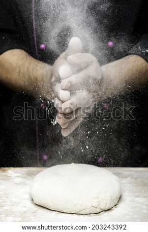 sprinkling flour with hands on bread dough