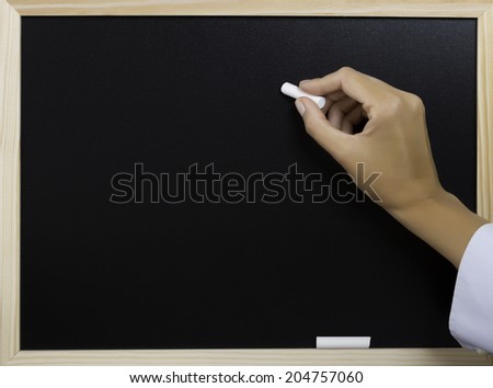 hand holding a white chalk writing on a blackboard