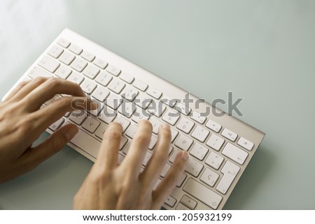 hands typing on the white wireless keyboard - focus on the left hand index finger