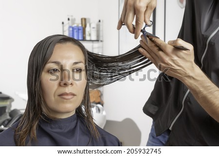 hairstylist is cutting the hair ends of a woman - focus on the hands of the hairstylist and the scissors