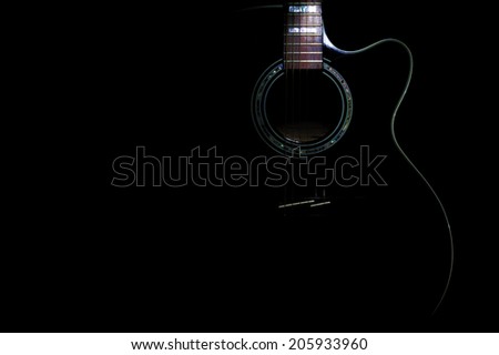 curves of a black body guitar lit - focus on the rosette