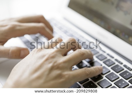 closeup of female hands typing on laptop keyboard - focus on a right hand - focus on the index knuckle
