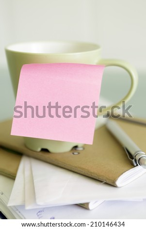 closeup of empty post-it and a coffee cup - focus on the post-it