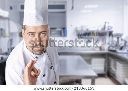 portrait of the master chef showing ok sign standing on a kitchen background - focus on the face