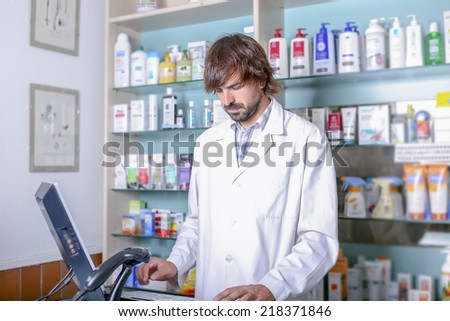 young male pharmacist using the computer in the pharmacy standing