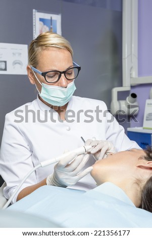 young female dentist with the tools in her hands is making a dental checkup to a female patient at the dental clinic