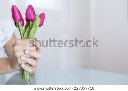 detail of the hands of the young woman holding a fuchsia bouquet of tulips