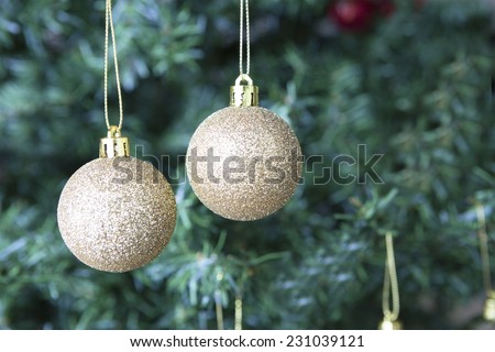 closeup of two shiny golden balls hung on a Christmas tree with copy space area - focus on the balls