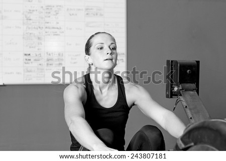young woman exercising on rowing machine in the gym - focus on the woman
