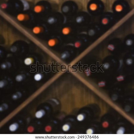 wooden wine rack unfocused with red wine bottles - useful as background