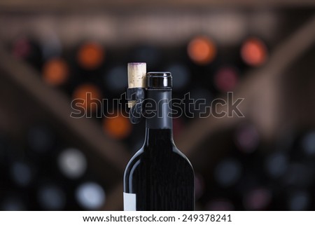 closeup of an opened bottle of red wine on a unfocused wine exhibitor background - focus on the bottle