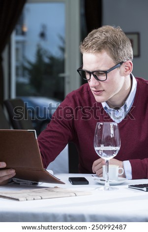 young businessman is checking the bill at the end of a working lunch at a restaurant - focus on the man face