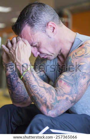 portrait of a male athlete on a pose concentrated with his hands on the forehead at the gym - focus on the man face
