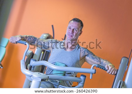 young man making seated rowing on a seated row machine - shoulder exercise - at the gym - finish exercise - focus on the man face
