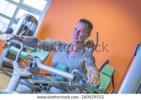 man making seated rowing on a seated row machine - shoulder exercise - at the gym - start exercise - focus on the man face