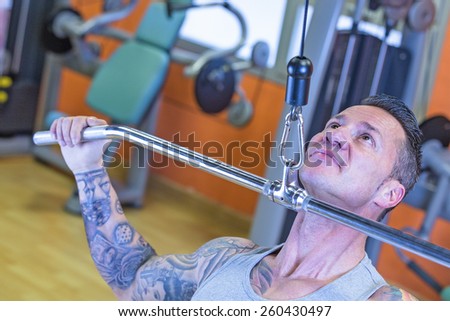 closeup of a man making lateral pull downs seated - dorsal exercise - at the gym - finish exercise - focus on the man face