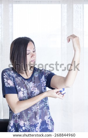woman is applying the sensor of the glucose monitoring system at the back of her arm with the applicator at home - focus on the woman eye