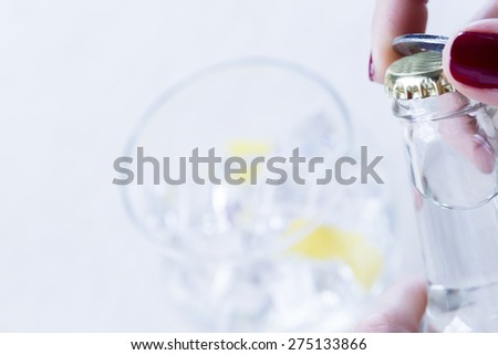 detail of a hand of a woman opening a tonic bottle on a gin tonic preparation session - focus on the bottle cap